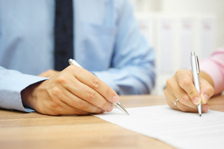 Businessman and woman hand signing agreement in office
